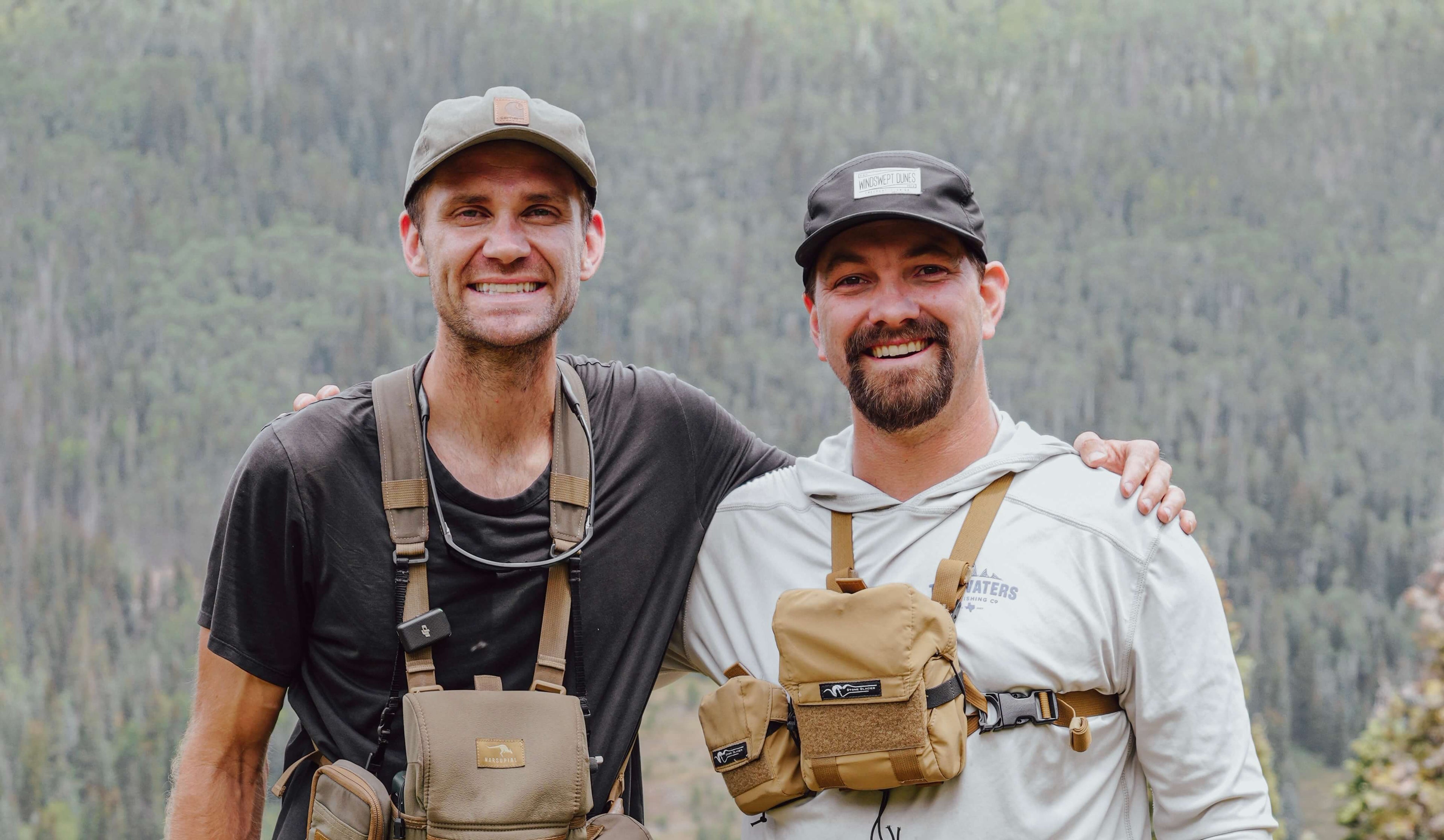 Two men wearing tactical gear in a forest setting